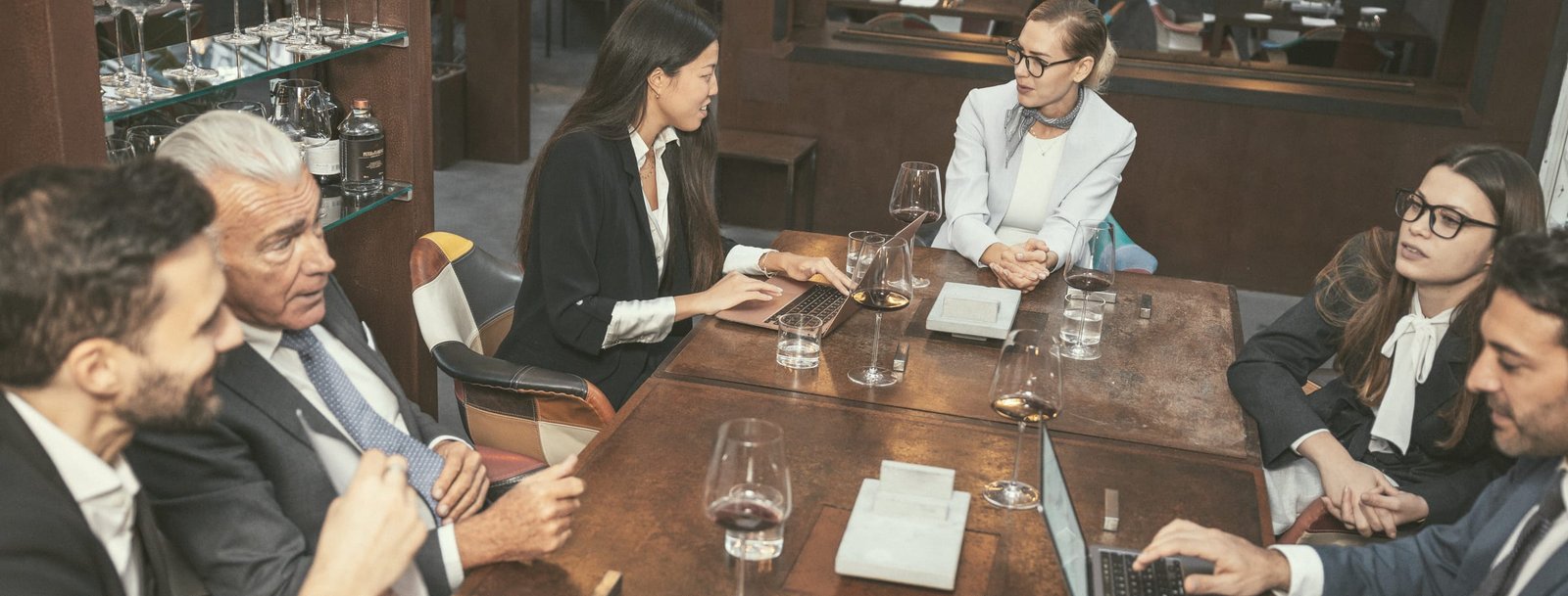 Réunion de direction dans une maison de vins : trois ou quatre personnes autour d’une table, organigramme ou documents de travail, cadrage large et sobre.